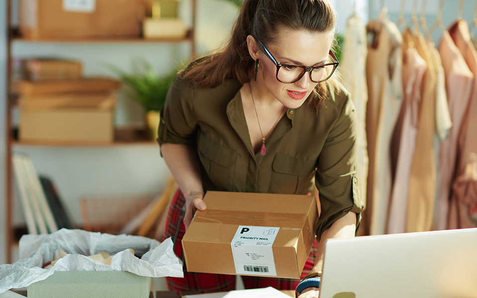 Online-Business-Banker-960x600 – Chemung Canal Trust Company  A woman in her office is in front of her computer with a small cardboard box package in her hand