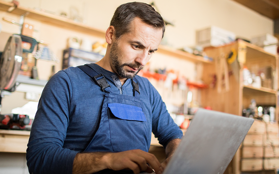 A man in an apron works at a computer