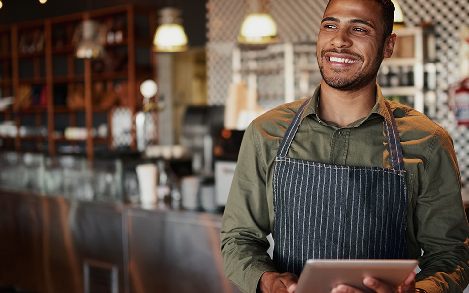 Small-Business-Loans-960x600 – Chemung Canal Trust Company  A man is standing in a cafe, wearing an apron