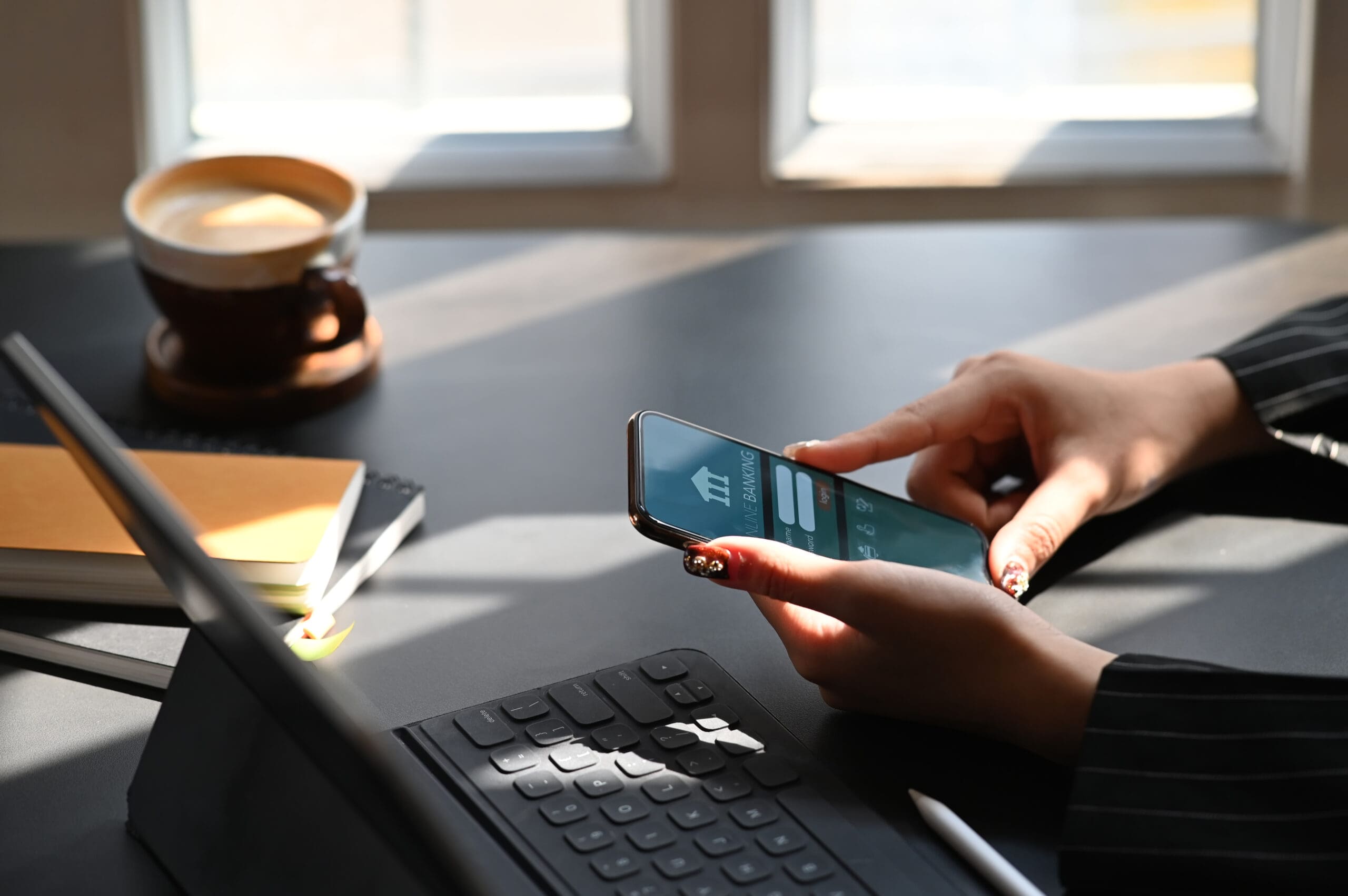 Cropped shot of executive woman holding smartphone in hands while doing online financial transaction by her smartphone in front computer tablet at the modern working desk – Chemung Canal Trust Company Cropped shot of executive woman holding smartphone in hands while doing online financial transaction by her smartphone in front computer tablet at the modern working desk