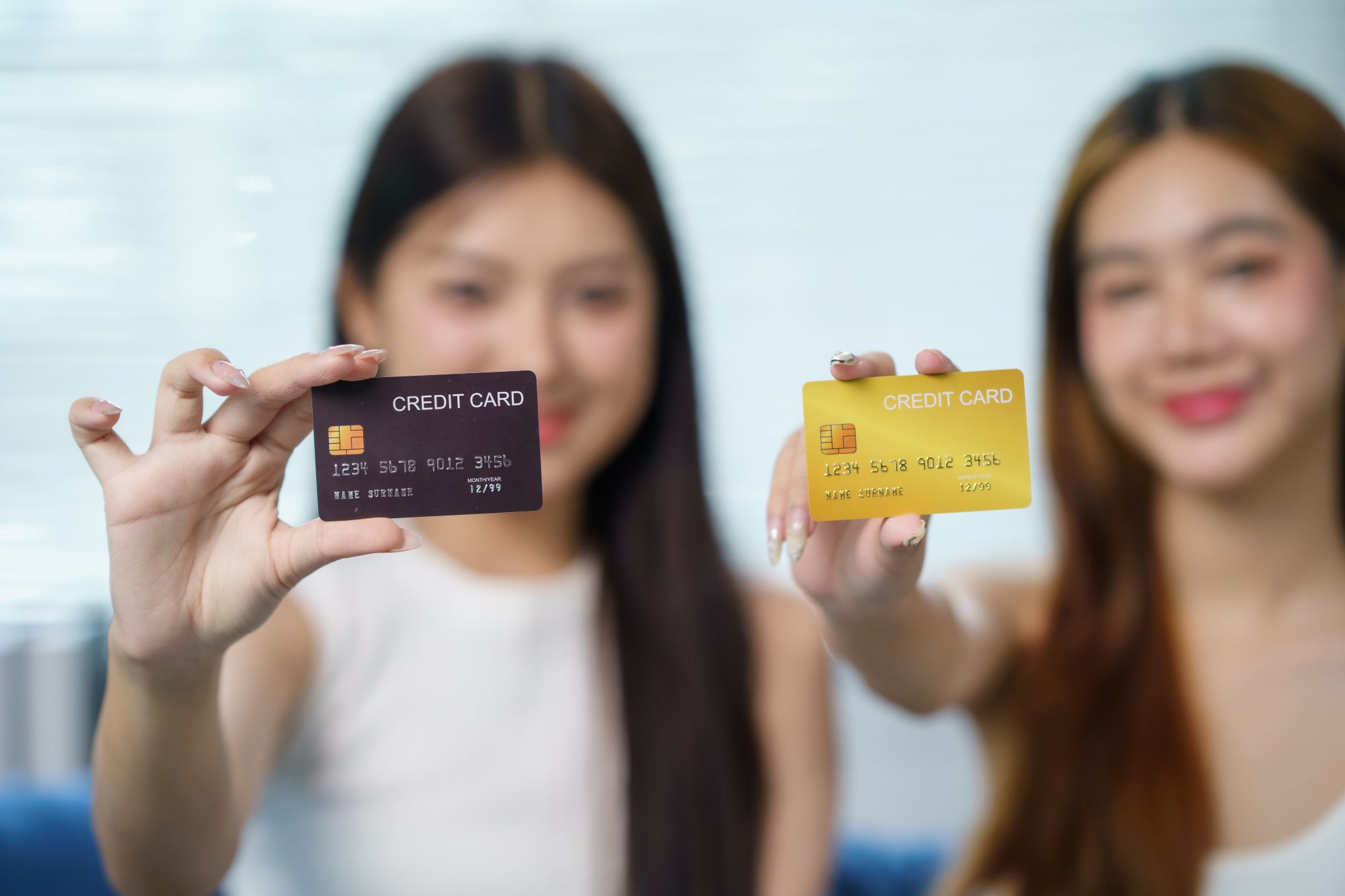 Women holding credit cards up to the camera