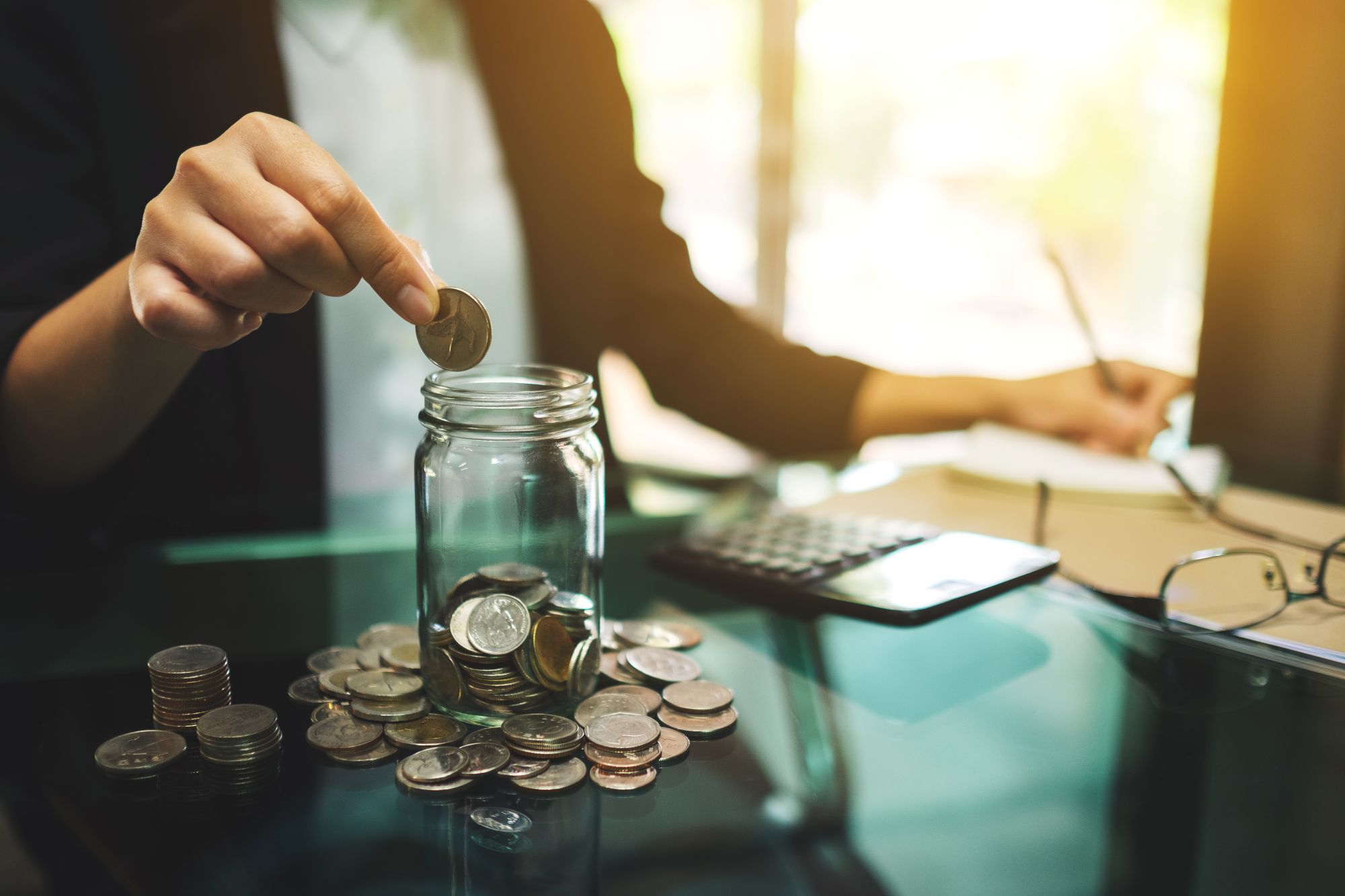 Business woman putting coins into a jar