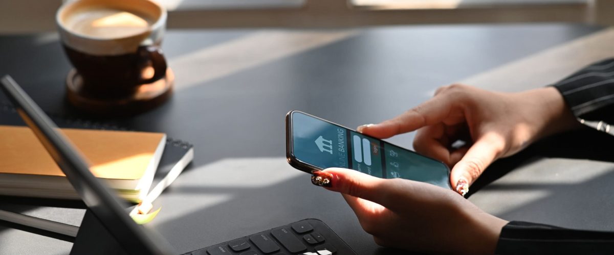Cropped shot of executive woman holding smartphone in hands while doing online financial transaction by her smartphone in front computer tablet at the modern working desk Cropped shot of executive woman holding smartphone in hands while doing online financial transaction by her smartphone in front computer tablet at the modern working desk