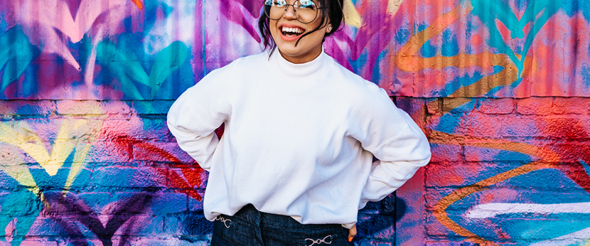 A woman is standing in front of a graffiti'd wall